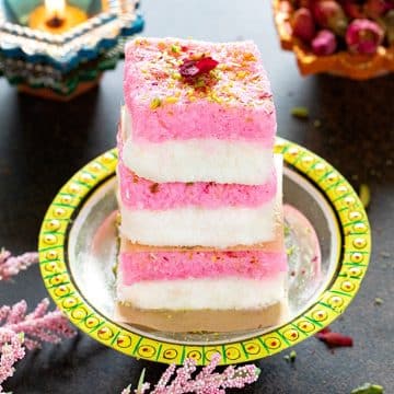 Layered coconut burfi stacked on a plate