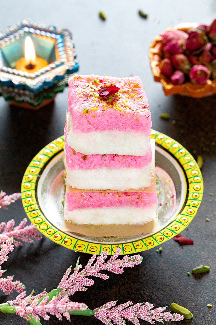 Layered coconut burfi stacked on a plate