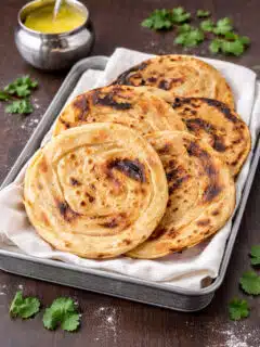 Homemade tandoori roti without oven served in a basket with ghee and cilantro