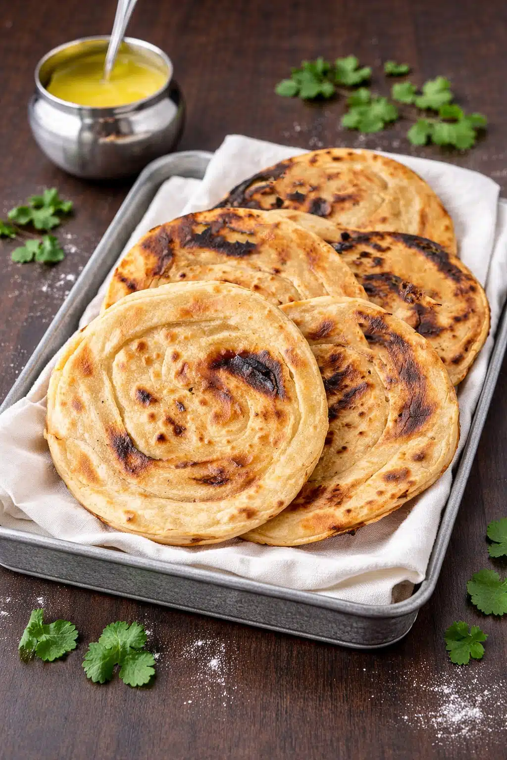 Homemade tandoori roti without oven served in a basket with ghee and cilantro