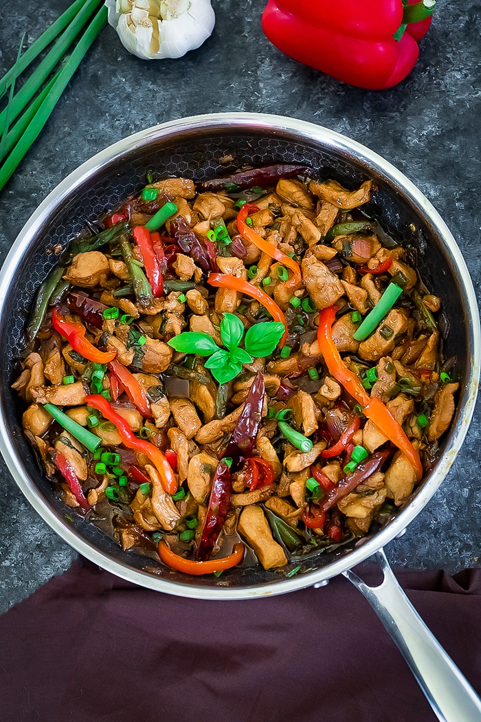 Thai Basil Chicken in a pan with bell pepper and basil leaves