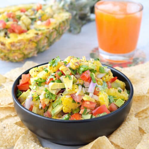 Colorful pineapple salsa with avocado and tomatoes in a serving bowl