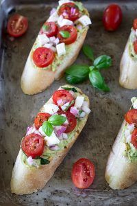 Tomato and Avocado Bruschetta on a tray with basil