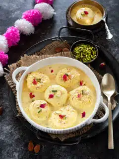 Rasmalai in a bowl garnished with rose petals
