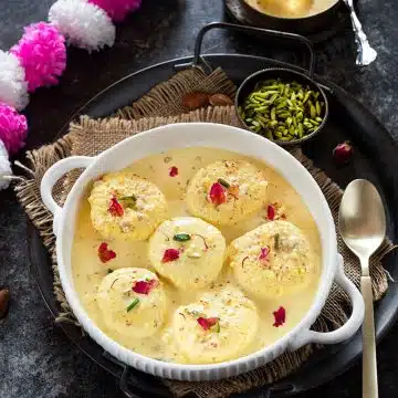 Rasmalai in a bowl garnished with rose petals
