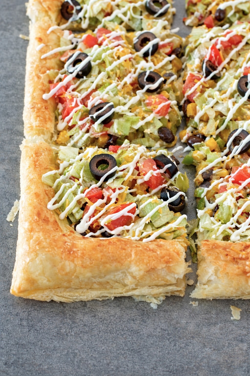 Crispy flaky puff pastry taco pizza sliced and served on a wooden board