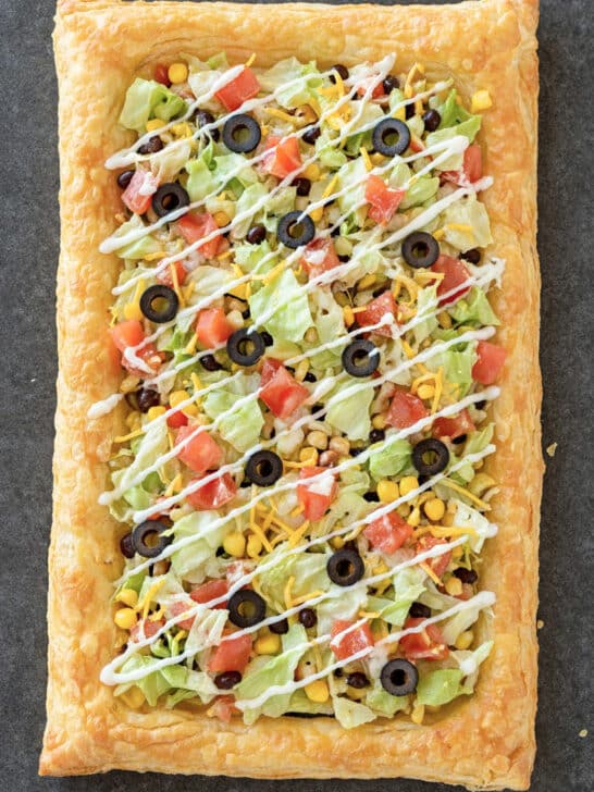 Easy Puff Pastry Taco Pizza topped with lettuce, tomatoes, olives, cheese, and sour cream