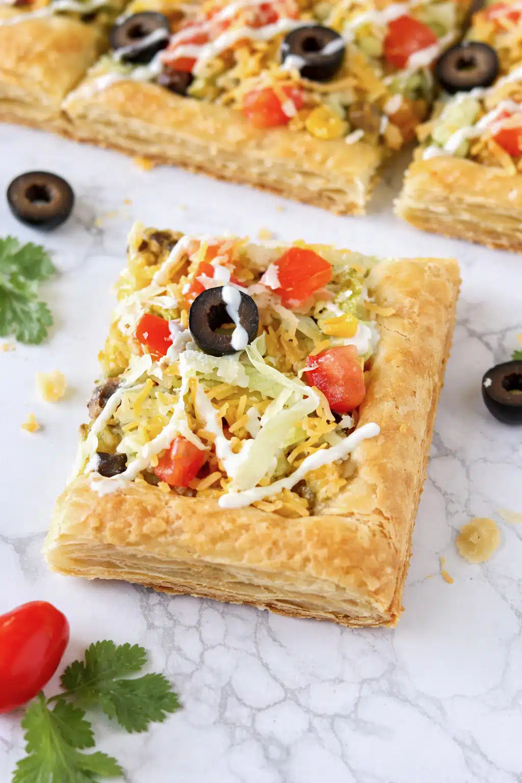 Golden baked taco pizza with fresh taco toppings and sour cream drizzle