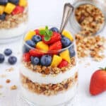 Berry parfait layered with vanilla yogurt, fresh strawberries, blueberries, mango, and crunchy granola
