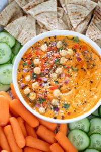 Roasted Red Bell Pepper And Chickpea Hummus garnished with herbs and onions