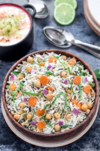 Instant Pot Chickpea and spinach Pulao with raita and two spoons - Ruchiskitchen