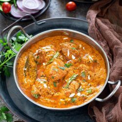 Chicken Tikka Masala in a pan garnished with cream and green chilies