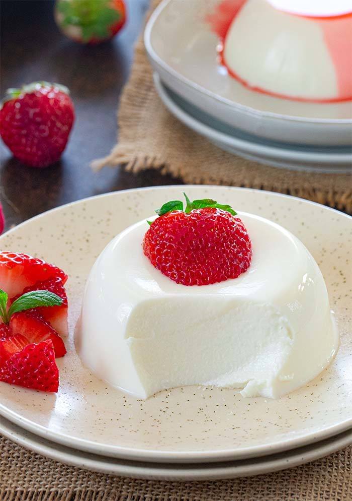 Sliced piece of panna cotta topped with strawberries