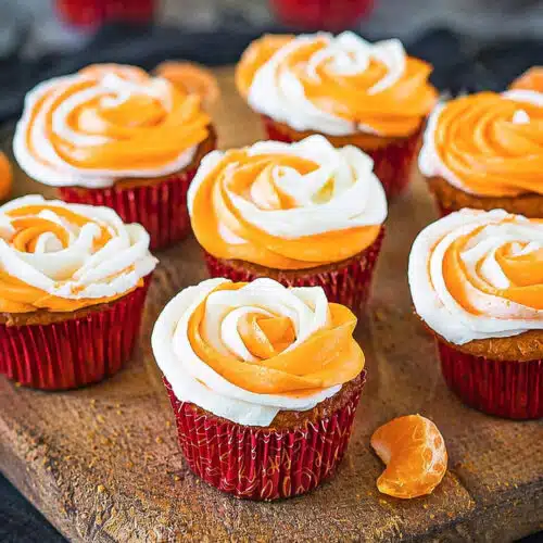 Eggless Orange Cupcakes frosted on a wooden tray