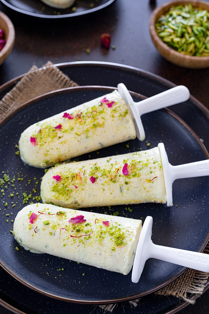 Kulfi in a plate specked with nuts and rose petals